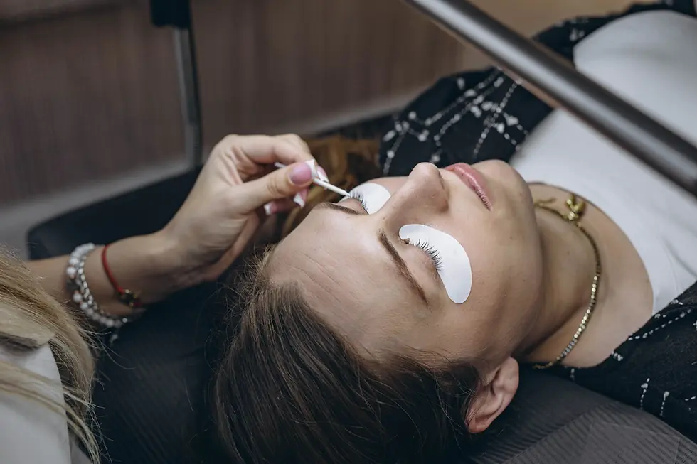 Wimpernverlängerung: Eine Kosmetikerin setzt einer liegenden Frau auf einer Liege mit Augenpads neue Wimpern ein.