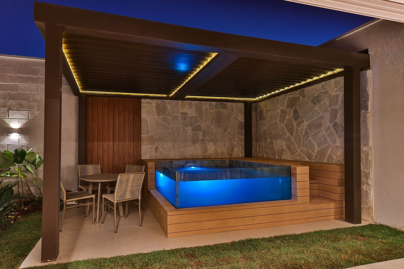 Spa elevado com visor de vidro iluminado sob pergolado em Brasília