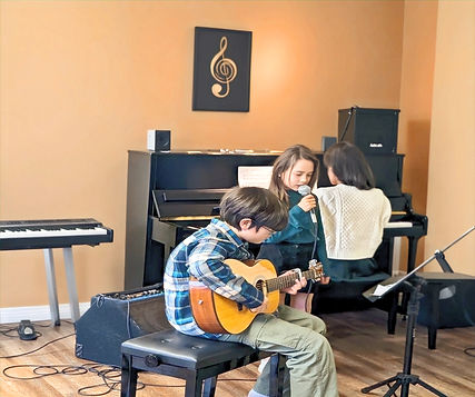 Students playing piano, guitar, and singing at InTune Music Windsor, learning music in a fun and supportive environment.