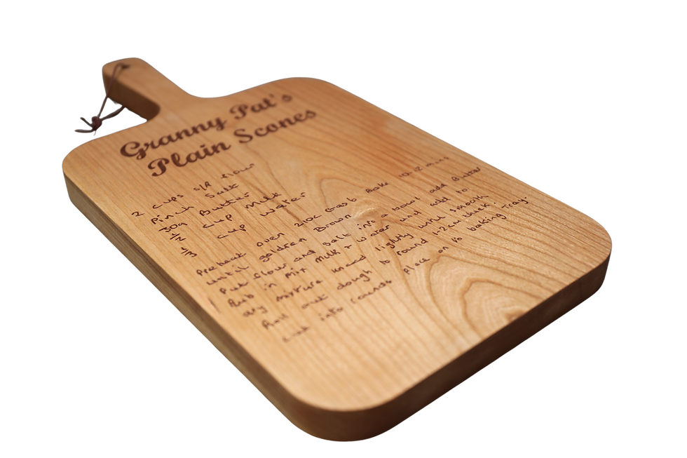 An angled wooden cutting board is engraved with a handwritten recipe for "Granny Pat's Plain Scones", including ingredients a