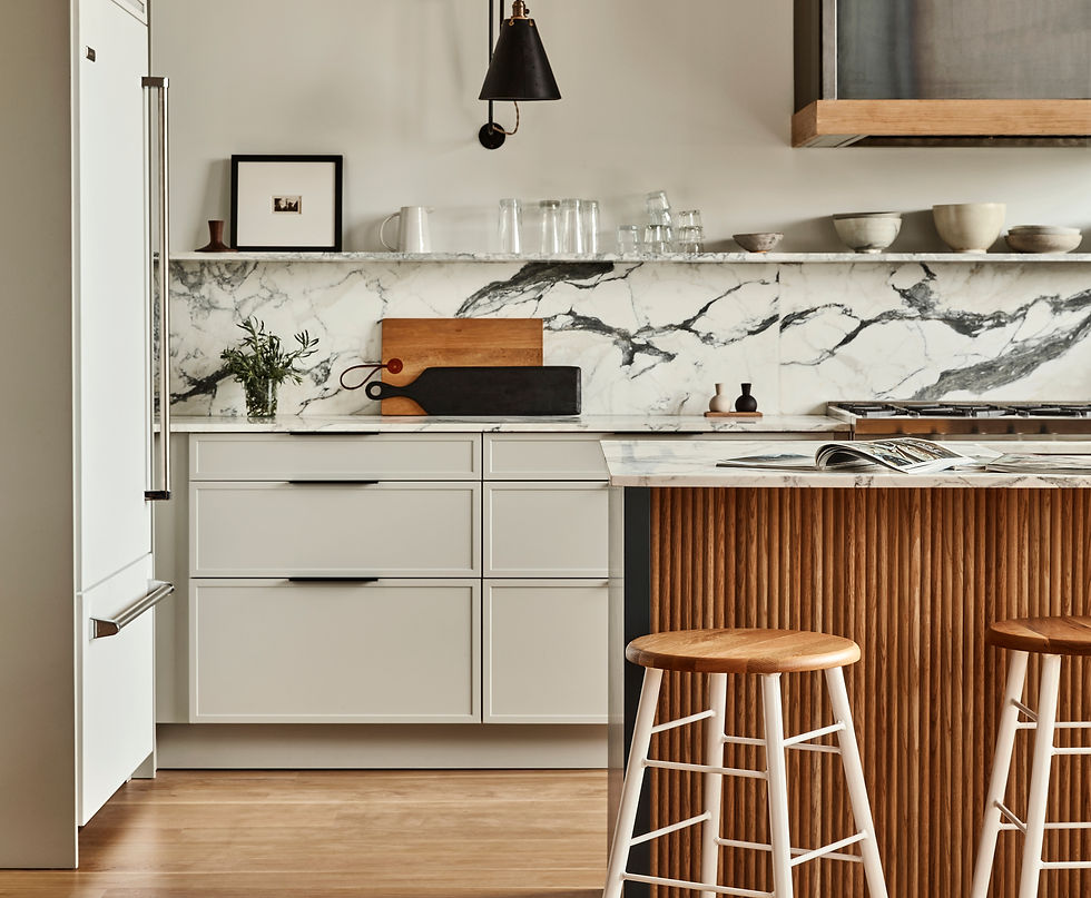 Modern kitchen with marble backsplash, white cabinets, wooden stools at a striped island, and open cookbook. Bright, minimalist style.