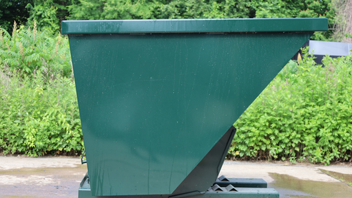 Green CCS self-dumping hopper on concrete with vegetation in background