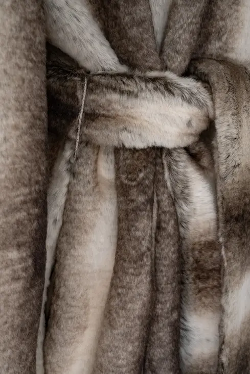 Detalle de textura del abrigo de pelo sintético Murmells, acabado suave en tonos beige y marrón.