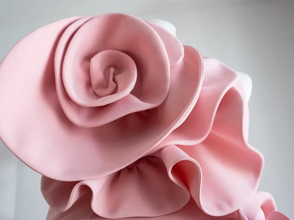 Textura y volumen de la flor 3D en tejido color rosa, detalle artesanal del vestido.