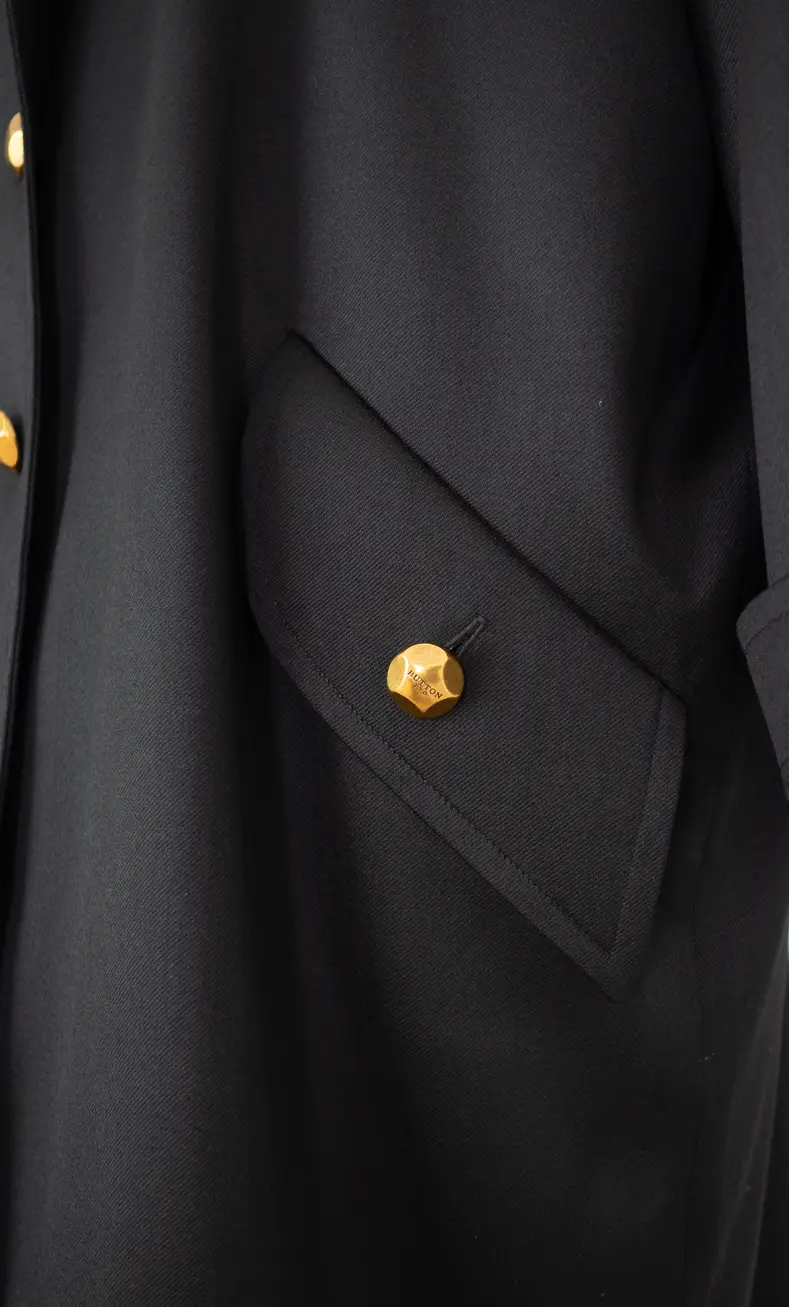 detalle de bolsillo con botón dorado de gabardina oversize inspirada en el trench militar.