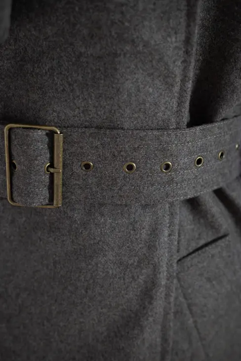 Detalle de cinturón con hebilla metálica en gabardina oversize de lana marrón, acabado de alta calidad