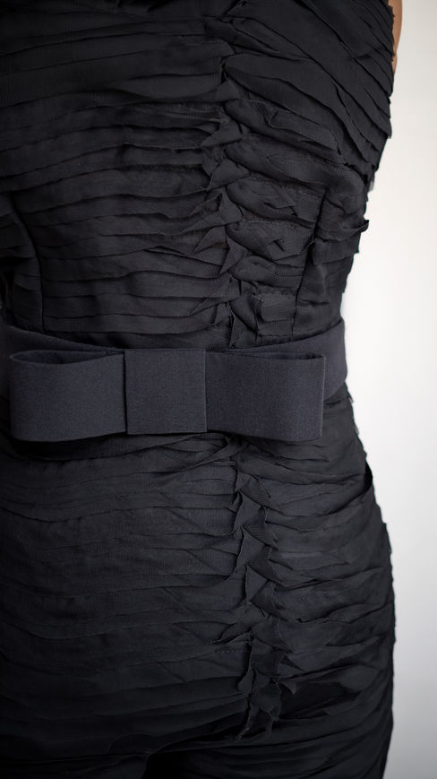 Detalle del lazo en crepé que define la cintura del vestido negro milhojas