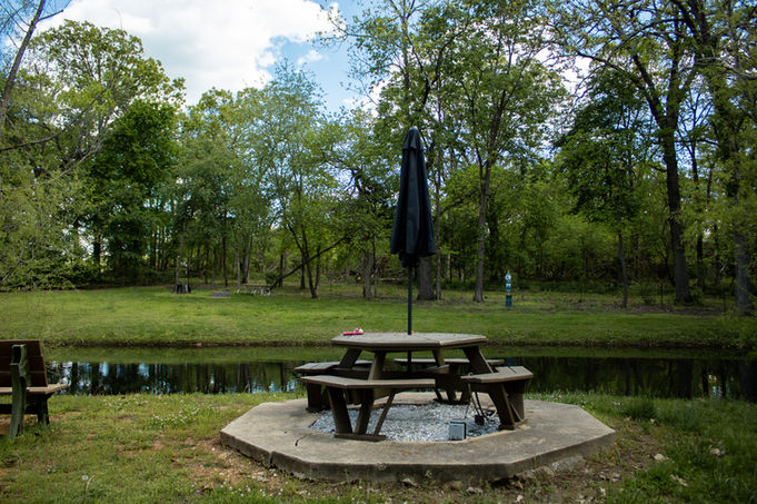 Picnic table near pond with umbrella, trees background, rv parks in joplin missouri