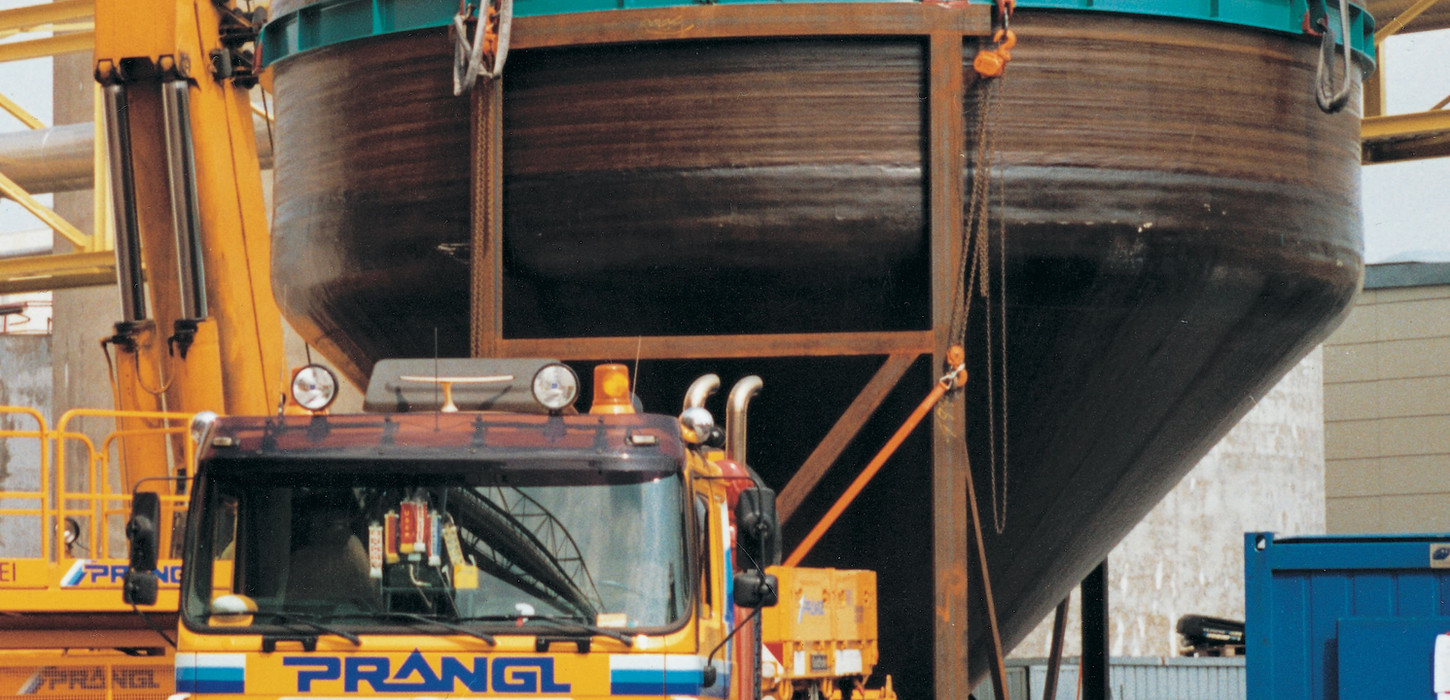 Ein gelber PRANGL MAN-Lkw transportiert ein massives Industrieschiff.