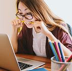 woman biting pencil while sitting on cha