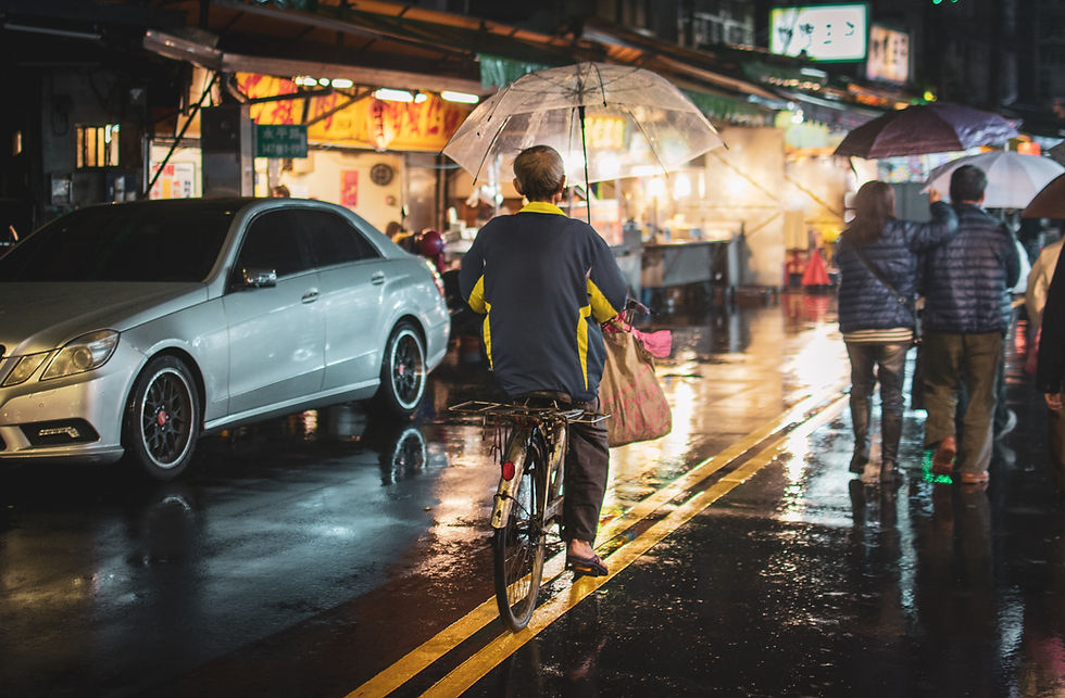 Cycling in the rain. A man cycling in the rain with an umbrella in one hand.