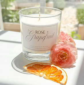Close up of a candle named Rose + Grapefruit.
Closeup of a candle named Rose + Grapefruit. Shown alongside a slide of citrus and a flower.