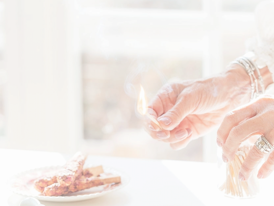 A woman is striking a match to light incense sticks.
