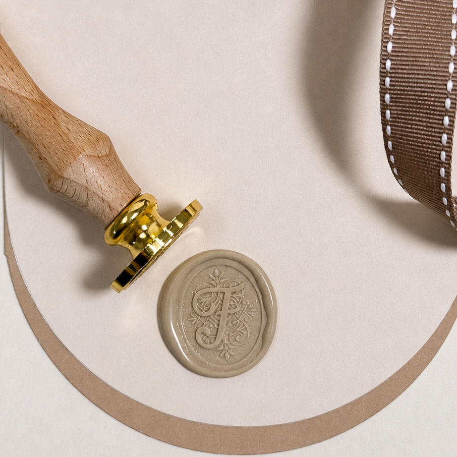Close up of Wax Seal & Stamp with the Letter F in Cursive Script on Curved Background with a Ribbon to the side