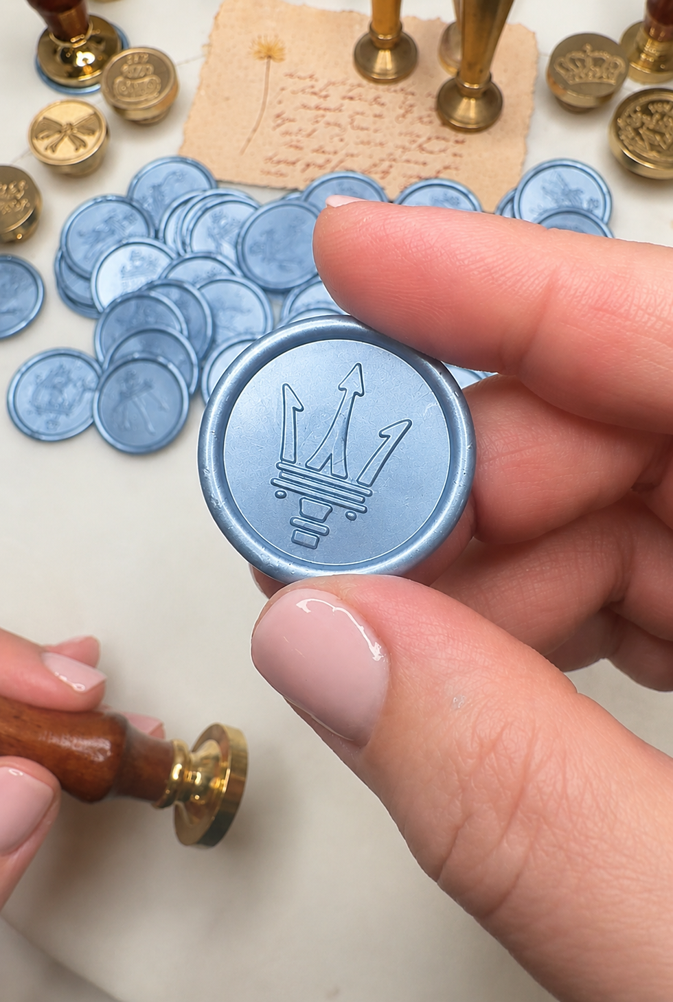 Close-up view of a custom wax seal featuring Maserati's Trident emblem on ice blue wax