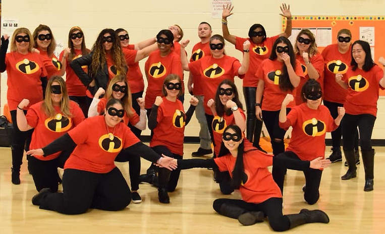 A team of teachers wearing matching red super hero shirts.