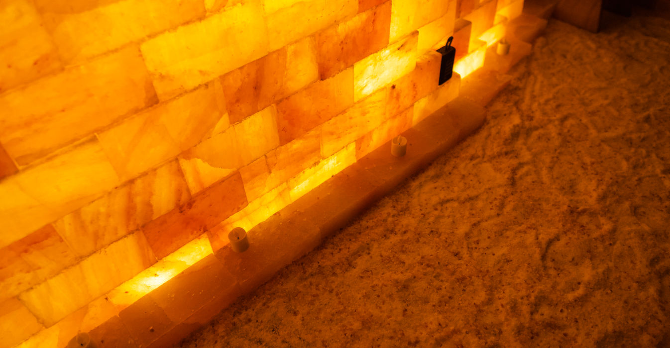 Warm glowing orange salt brick wall and granular salt floor. at Thrive Hive Health in Upland, CA