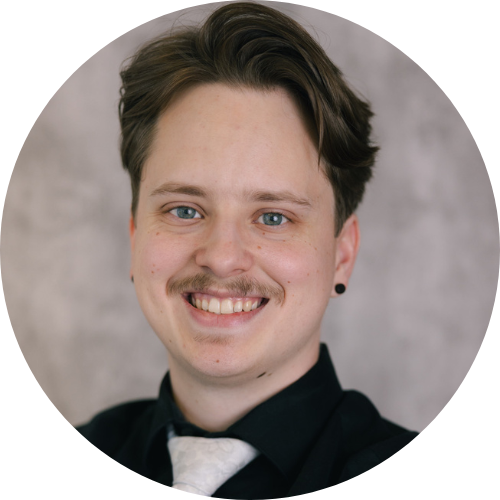Smiling person with short dark hair and a mustache.