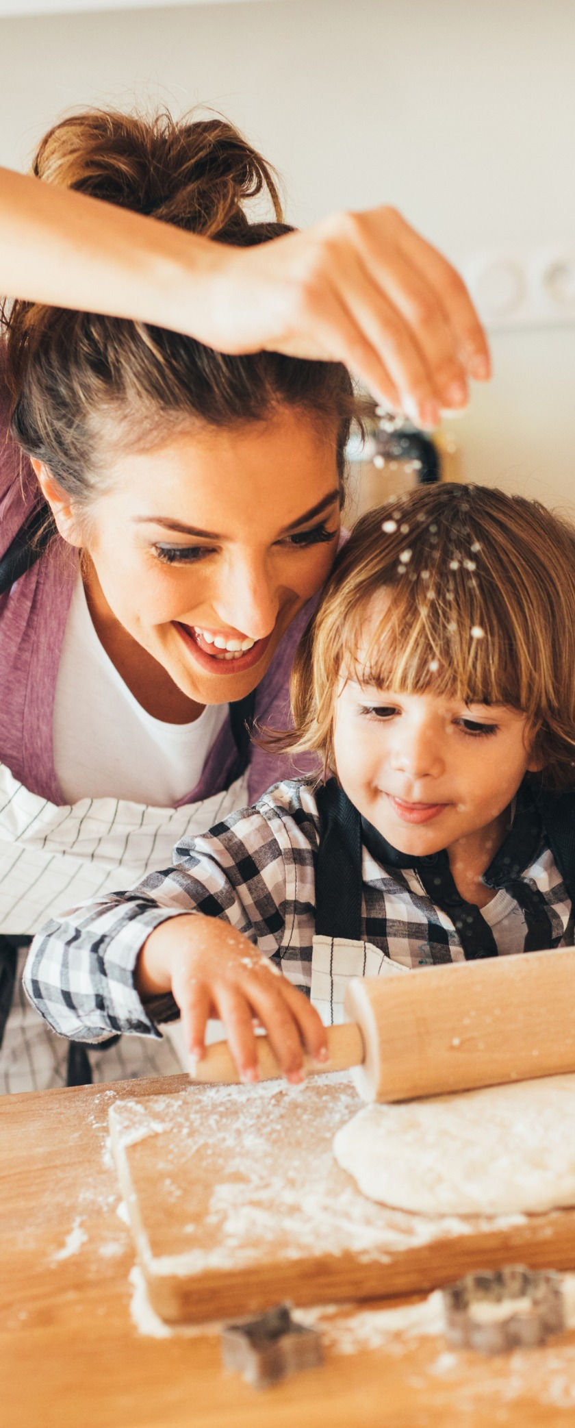Woman and child smiling while baking together.