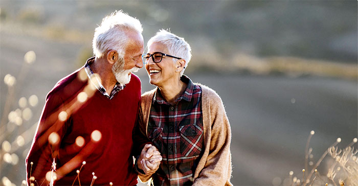 Smiling senior couple holding hands and walking outdoors