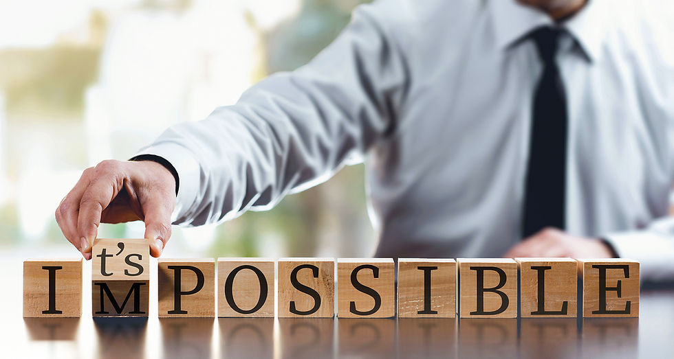 Hand changing 'impossible' to 'possible' using wooden blocks.