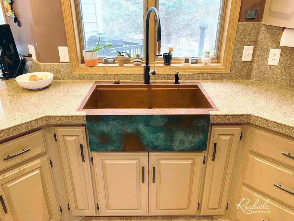 Copper sink with faucet, white cabinets, and Rachiele in the kitchen.