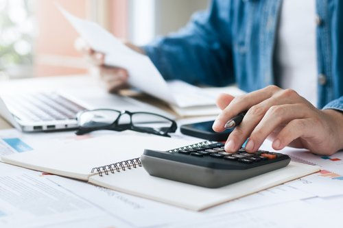 Person using a calculator and reviewing financial documents