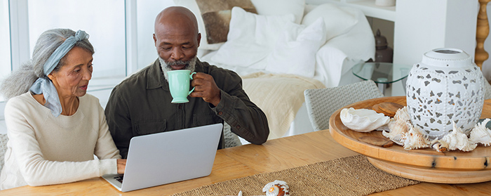 Senior man drinking coffee while using a laptop