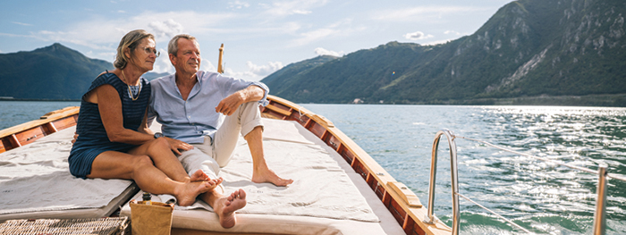 Senior man relaxing on a wooden boat with mountain views