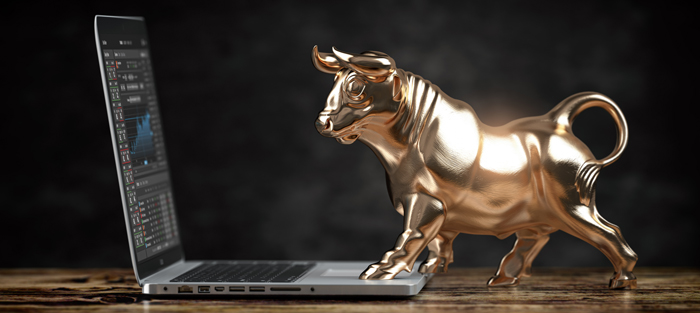 Golden bull statue standing on a laptop keyboard.