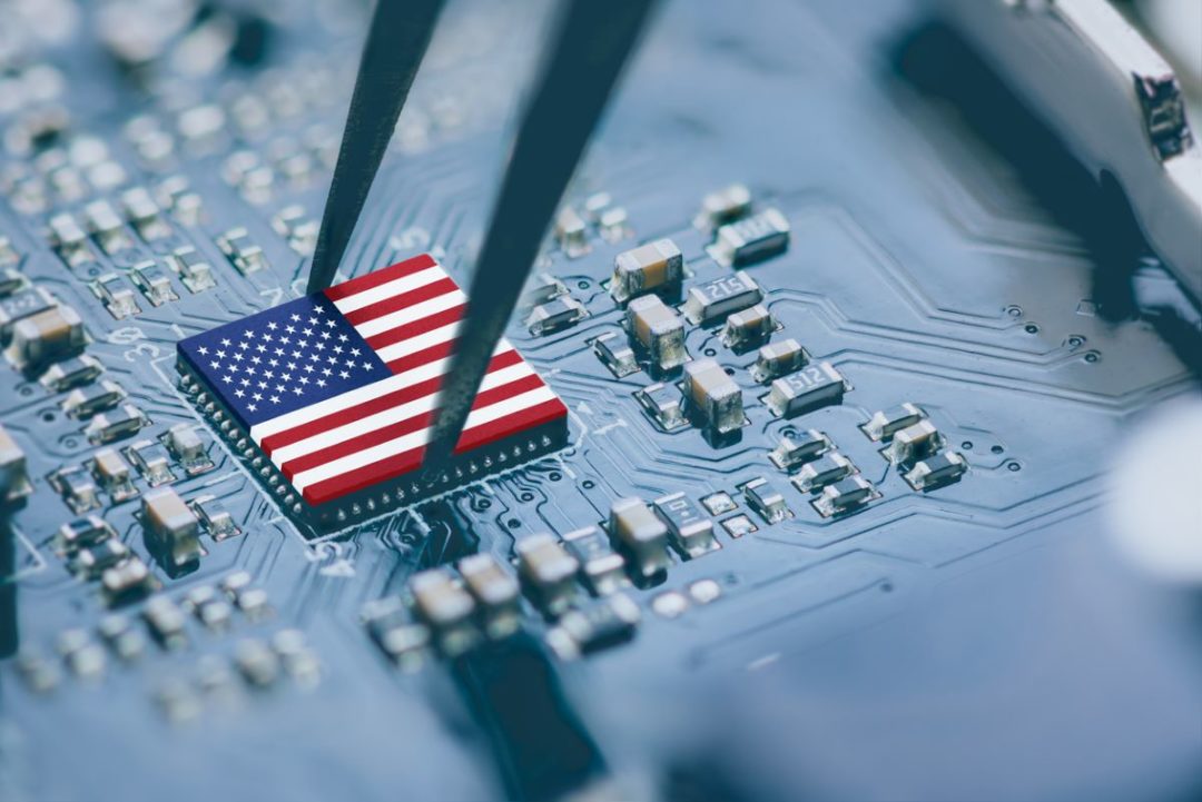 Tweezers placing an American flag microchip on a circuit board