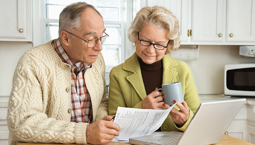 Senior couple reviewing financial documents at a laptop