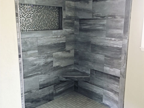 Stone look tile shower and mosaic on niche box and shower pan.