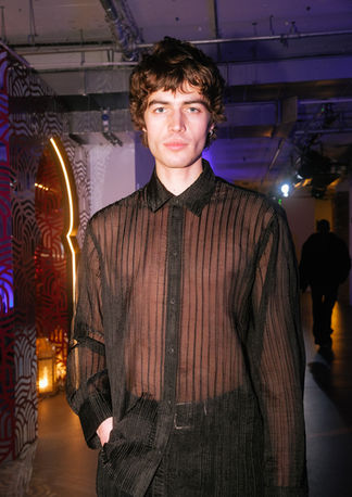 Thomas Maecock posing at an event while wearing an outfit from the Chet Lo x Pull & Bear collection. Event photography by Betka Bulikova.