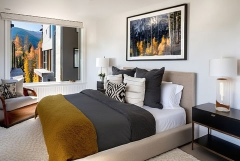 Basalt townhome bedroom design featuring upholstered bed, mountain views, modern nightstands, warm textiles, and photography inspired by the surrounding forest.

