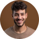 Smiling young man with curly hair and beard looking forward.
