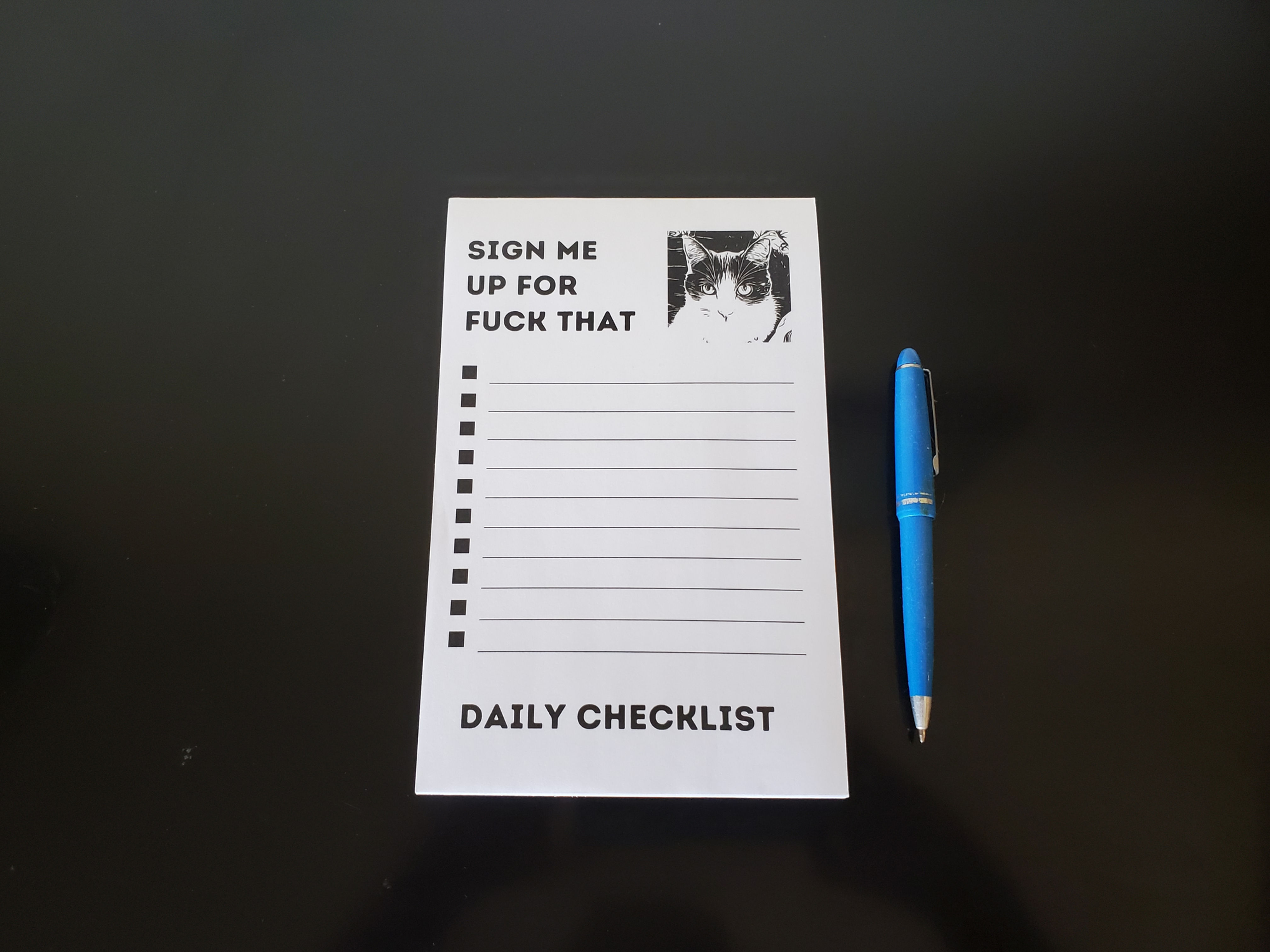 Adult Humor Notepad Daily Checklist with a black and white illustrated cat and the message Sign Me Up for Fuck That