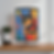 Colorful lamp with abstract cat design and tulips on a wooden table. Blue, orange, and green tones. Potted plant beside it.