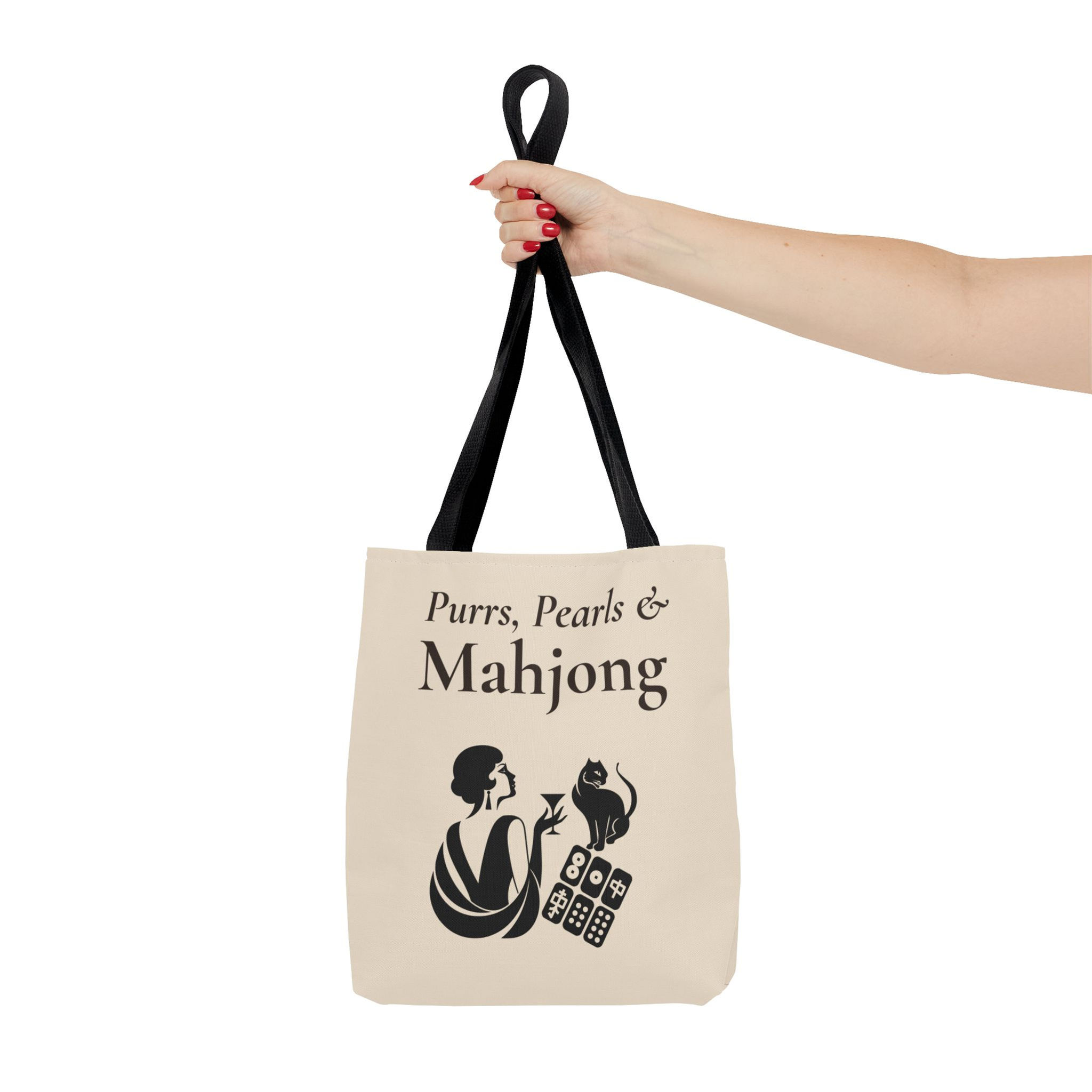 Hand holding the black straps of a Mahjong Tote Bag with an art deco illustration of a flapper and a cat