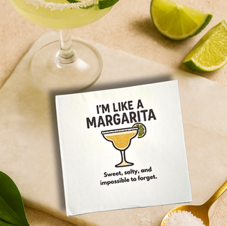 Cocktail Napkin with the Slogan I'm Like a Margarita on a table next to a margarita glass and limes