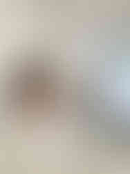 Ola Farahat standing near the kitchen counter while her daughter sits on the countertop in her arms, with a vase of flowers on the side in a bright modern kitchen.