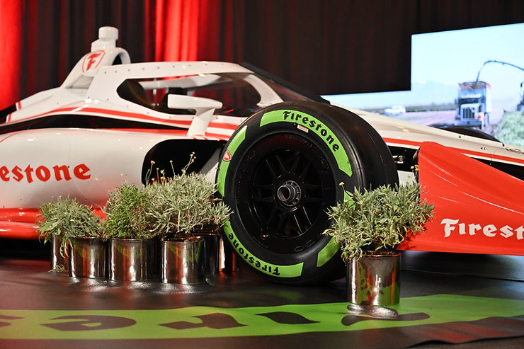 An IndyCar in the background with guayule plants on the front
