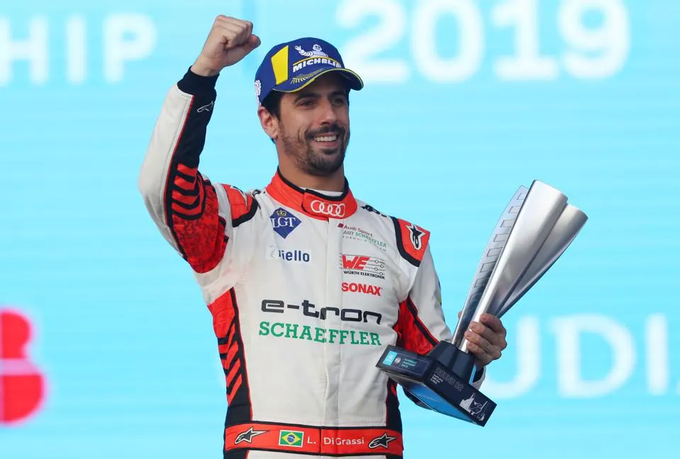 Lucas di Grassi, who is a Formula E driver, smiling and holding a silver trophy
