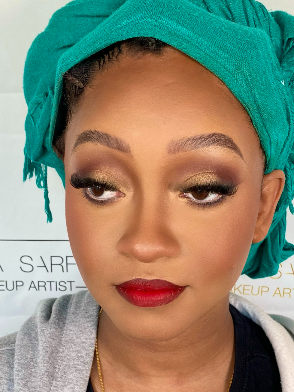 Woman with vibrant makeup and teal headscarf.