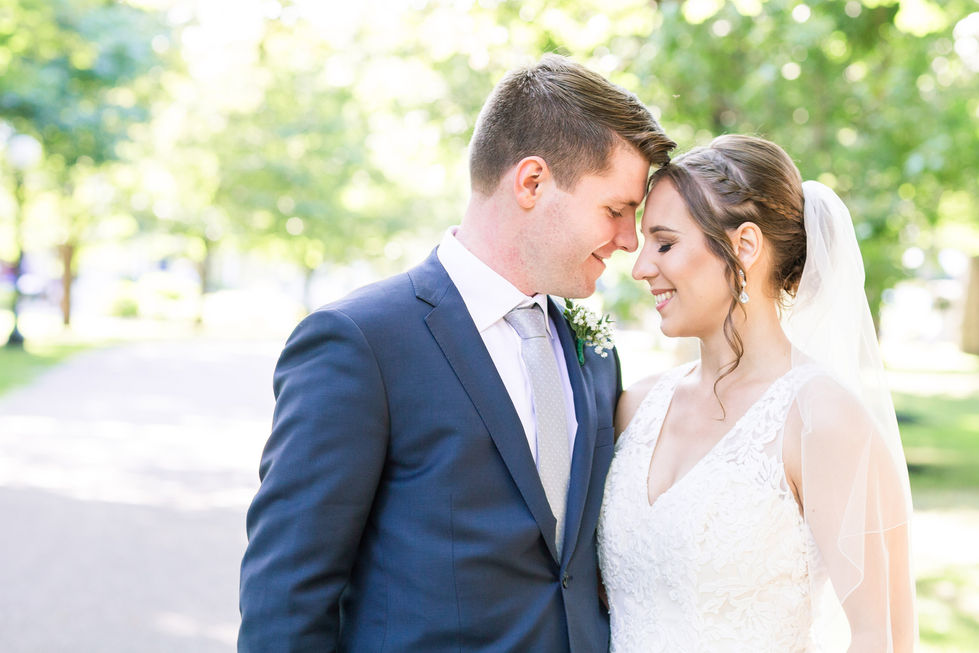 Bride and groom embracing outdoors, smiling warmly.