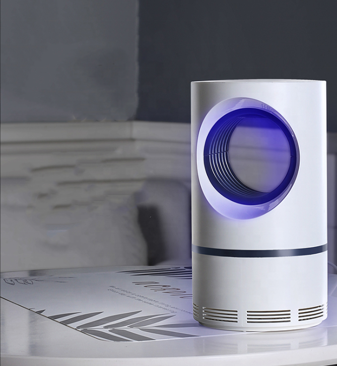 White cylindrical mosquito killer with a circular violet-blue illuminated opening on a table