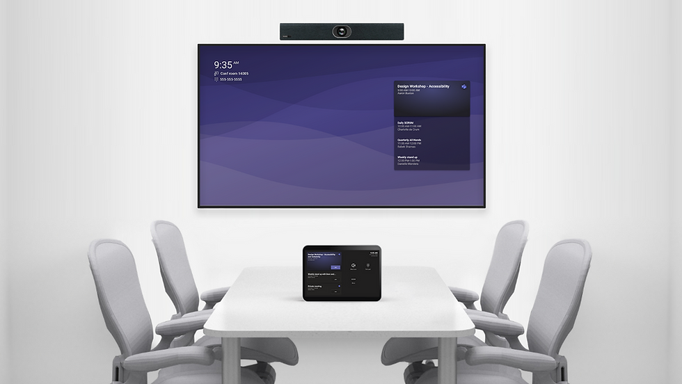 Conference room with four chairs around a table. A wall screen displays a purple interface with text. A device on the table mirrors it.
