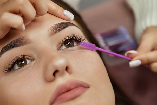 master combs the eyelashes of the client after the eyelash extension procedure. close-up.
