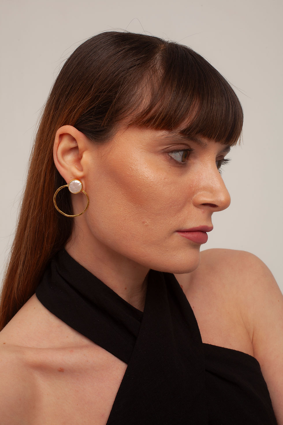 Woman wearing gold hoop earrings with pearl