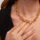 Thumbnail: Woman wearing gold chain necklace with green accents